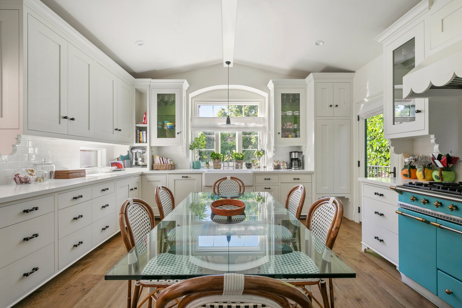 Emma Stones kitchen with white cabinetry glass table blue range white scalloped vent hood