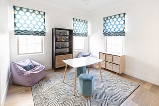 blue shades with white circle pattern pulled halfway down three windows in whitewalled children's playroom with white...