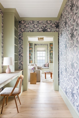 leafy patterned wallpaper green trim desk facing window beside green shelves