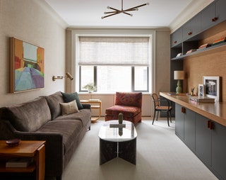 lower shelves with countertop overhand of a desk space window on far wall to left brown sofa glass cocktail table