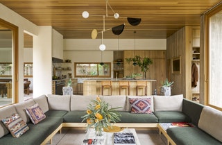 Sunken living room in open concept space with twotoned green and white sofa around a square cocktail table kitchen...