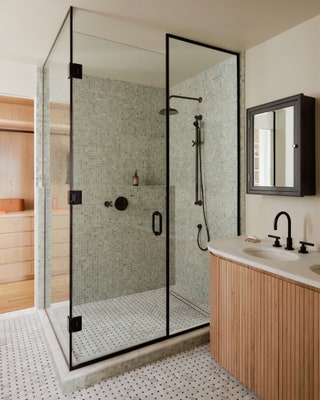 The primary bathroom continues the bedrooms neutral palette anchored by a custom vanity made from white oak and Carrara...