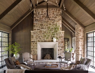 Featuring a vaulted ceiling and a dramatic chandelier this farmhouse living room draws the eye upward. Jeffrey Dungan...